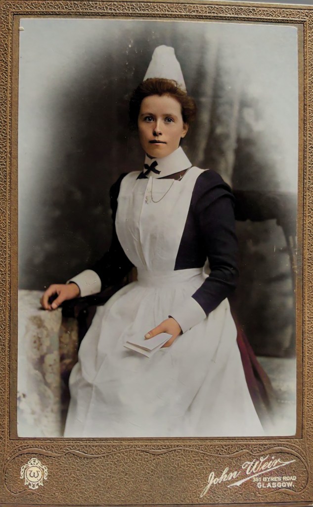 A vintage portrait of a female nurse dressed in a traditional uniform with a white apron and cap, seated while holding a small book, against a softly blurred background.
